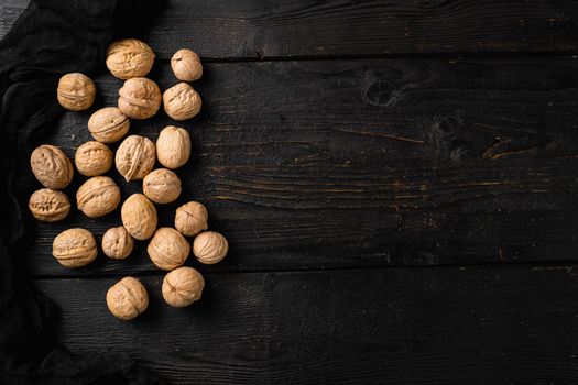 Walnut whole nut set, on black wooden table background, top view flat lay, with copy space for text