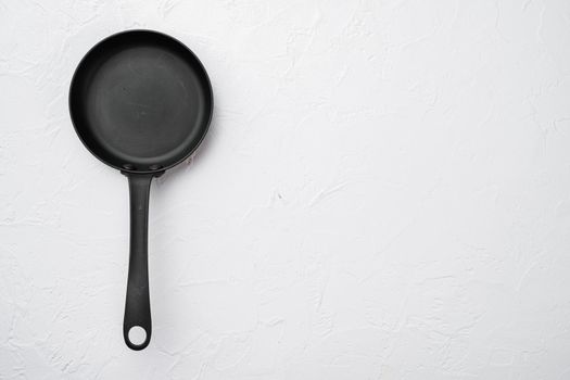 Large frying pan set with copy space for text or food with copy space for text or food, top view flat lay, on white stone table background