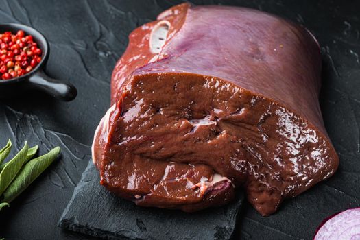 Raw beef liver on black background.