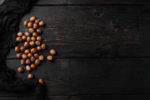 Heap or stack of hazelnuts set, on black wooden table background, top view flat lay, with copy space for text