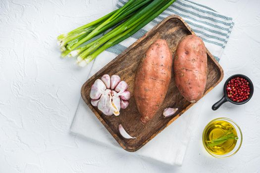 Raw whole sweet potatoe with spices on white background, flat lay.