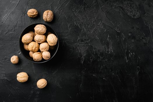 Whole organic walnuts set, on black dark stone table background, top view flat lay, with copy space for text