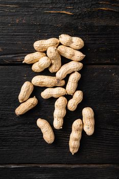 Peanut in a shell set, on black wooden table background, top view flat lay