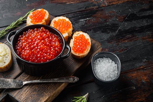 Canape toasts with red caviar, on old dark wooden table background with copy space for text