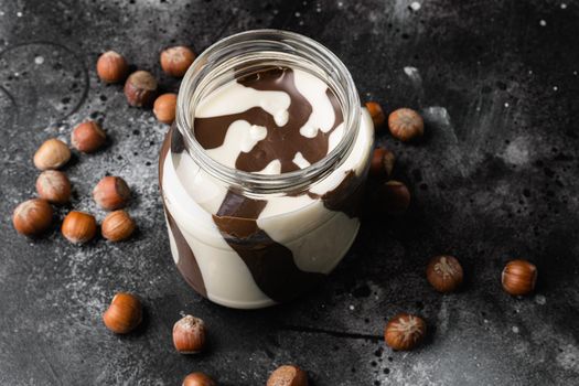 Hazelnut spread with nuts set, on black dark stone table background