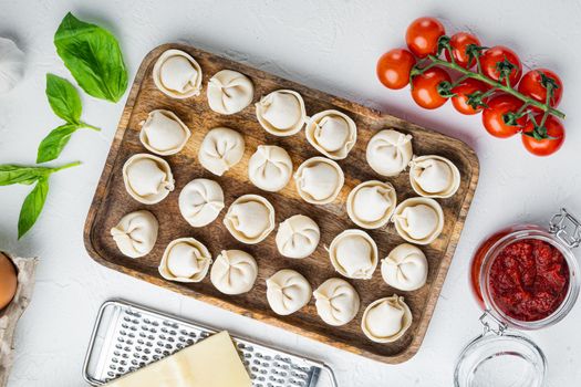 Tortellini with Parmesan and Basil set in wooden tray, on white background, top view flat lay