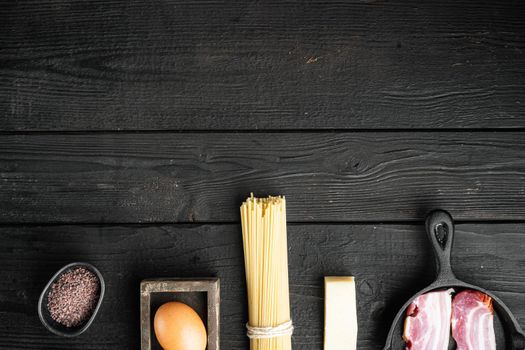 Fresh raw ingredients for traditional italian pasta Carbonara set, on black wooden background, top view flat lay, with copy space for text