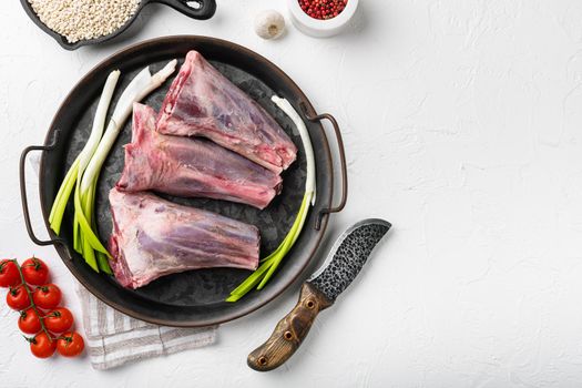 Raw lamb shanks with pearl barley and ale set, on white stone table background, top view flat lay, with copy space for text