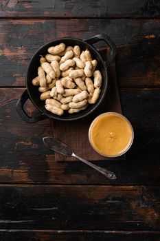 Creamy and smooth peanut butter in jar set, on old dark wooden table background, top view flat lay, with copy space for text