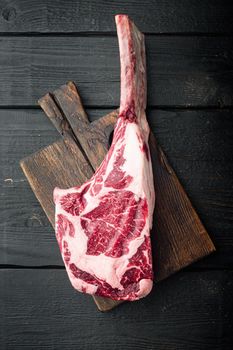 Tomahawk raw fresh beef steak with spices set, on black wooden table background, top view flat lay