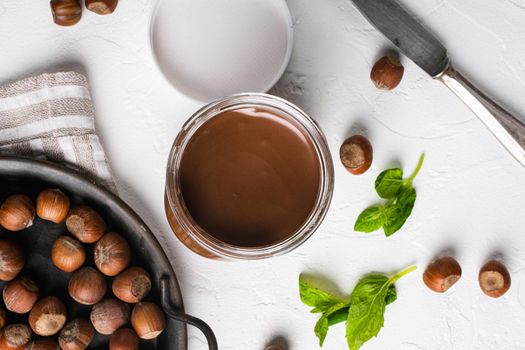 Chocolate spread or nougat cream with hazelnut set, on white stone table background, top view flat lay
