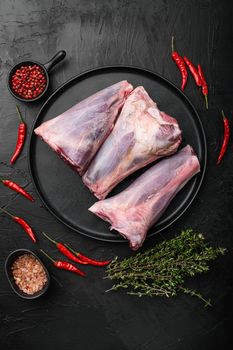 Fresh lamb shank set, on black dark stone table background, top view flat lay