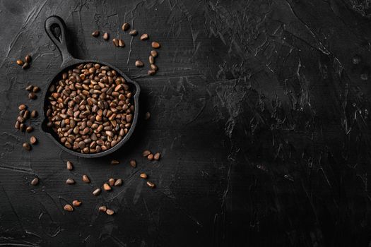 Pine nuts set, on black dark stone table background, top view flat lay, with copy space for text