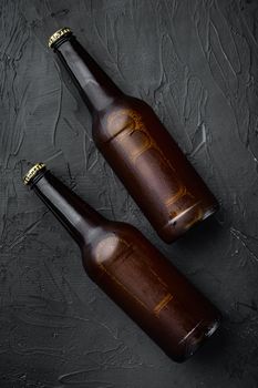 Fresh beer in glass bottles set, on black stone background, top view flat lay