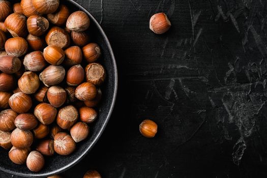 Heap or stack of hazelnuts set, on black dark stone table background, top view flat lay, with copy space for text