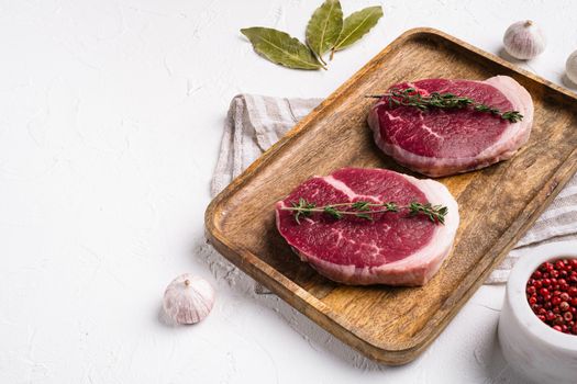 Raw tenderloin steak set, on white stone table background, with copy space for text