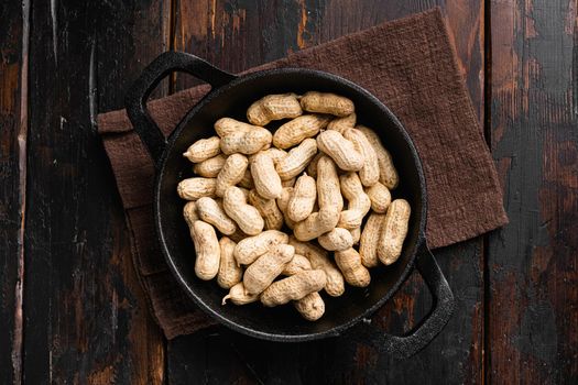 Organic peanuts in shell set, on old dark wooden table background, top view flat lay