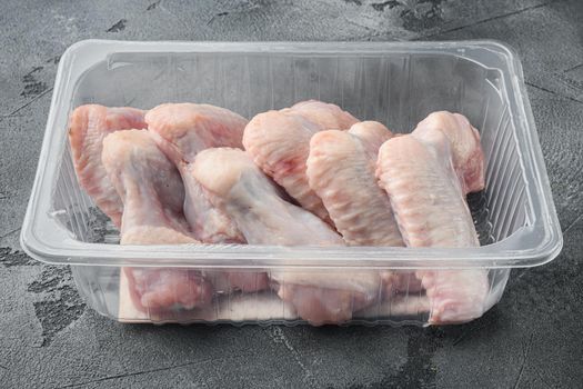 Fresh chicken wings spit in plastic vacuum pack set, on gray stone background