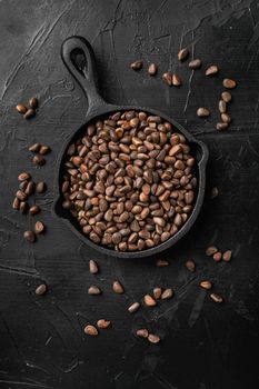 Pine wild organic nut set, on black dark stone table background, top view flat lay