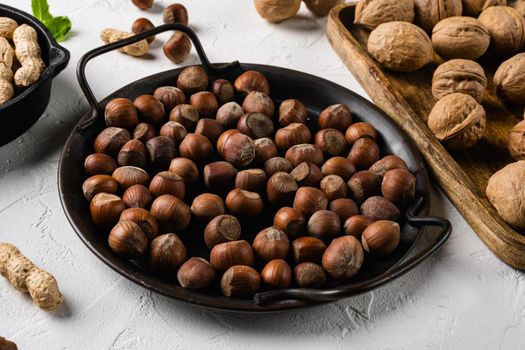 Hazelnuts brown wooden shell set, on white stone table background