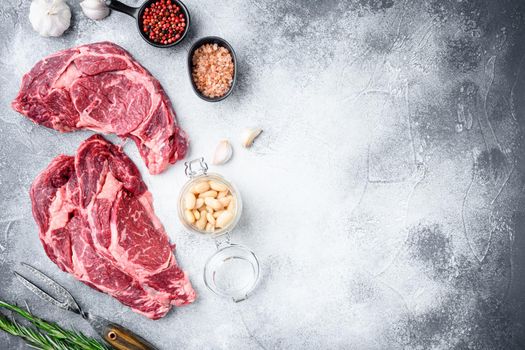 Rib eye steak of beef marbled meat or scotch fillet set, on gray stone background, top view flat lay, with copy space for text