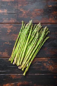 Raw organic asparagus on dark wooden old background, top view