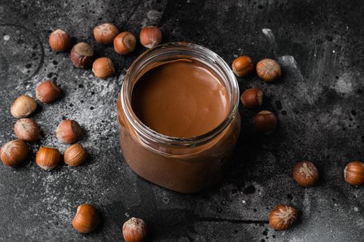 Chocolate spread or nougat cream with hazelnut set, on black dark stone table background