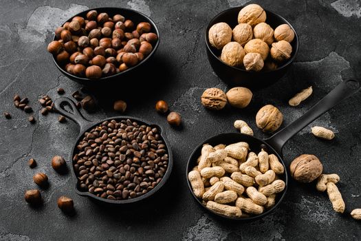 Assortment of nuts in shells, peanut, walnut, pine nuts and hazelnut set, on black dark stone table background