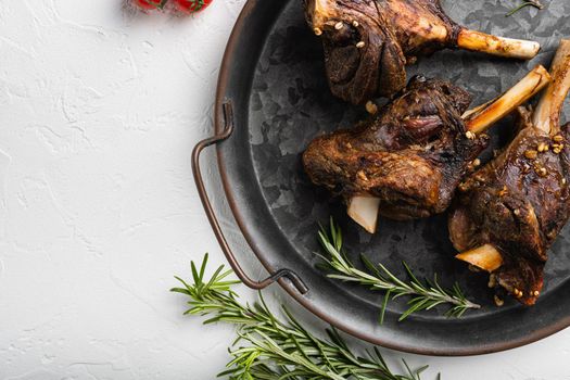 Lamb shanks cooked in a rich gravy set, on white stone table background, top view flat lay, with copy space for text