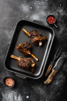 Slow Cooked Lamb Shanks meat set, on black dark stone table background, top view flat lay