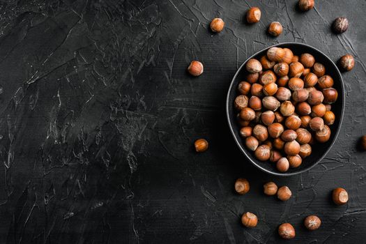 Hazelnuts brown wooden shell set, on black dark stone table background, top view flat lay, with copy space for text