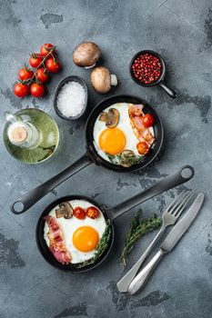 Scrambled eggs in frying pan with pork lard, bread and green feather in cast iron frying pan, on gray background, top view flat lay