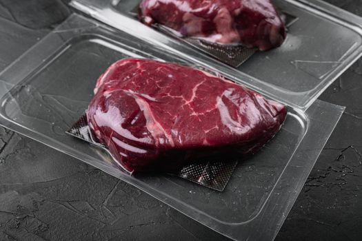 Market pack with raw rump beef steak set, on black dark stone table background, with copy space for text