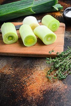 Organic chopped leek for cooking Braised Leeks on wooden board with herbs ingredients , on rustic metall background dark, side view