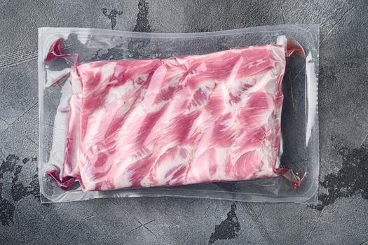 Pork ribs in a vacuum bag set, on gray stone background, top view flat lay