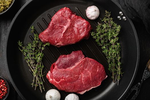Raw beef meat steak with herbs set, on black wooden table background, top view flat lay