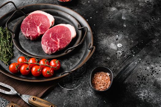 Fresh raw organic beef steak set, on black dark stone table background, with copy space for text