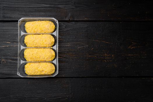 Chicken cutlets in breadcrumbs set, in plastic market container, on black wooden table background, top view flat lay, with copy space for text