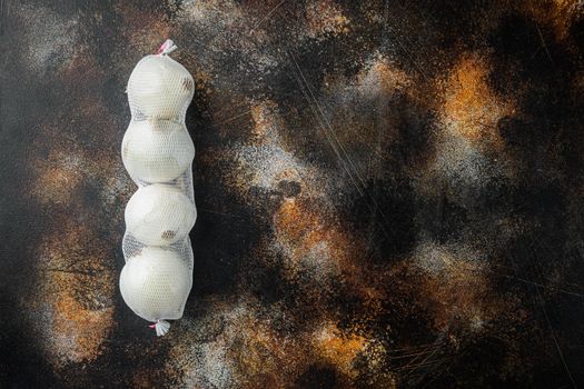 Homegrown white onions, on old dark rustic background, top view flat lay with copy space for text