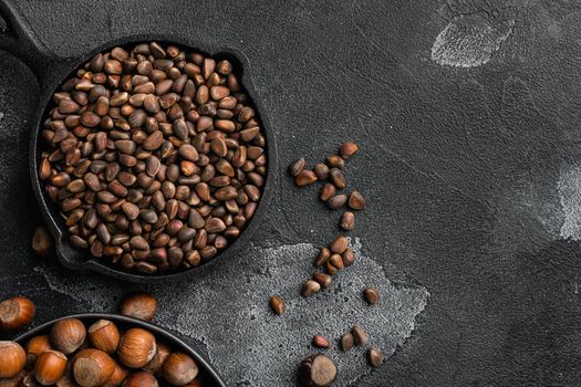 Cedar wild organic nut set, on black dark stone table background, top view flat lay, with copy space for text