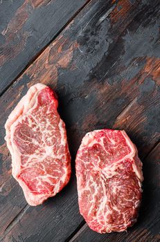 Top blade organic meat cut, raw marbled beef steak, On dark wooden background, top view with space for text