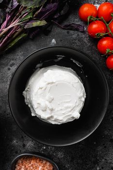 A fresh ricotta set, on black dark stone table background, top view flat lay