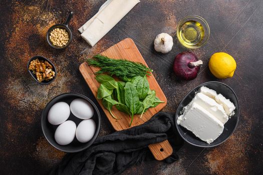 Traditional greek spanakopita ingredients filo spinach eggs feta top view on dark background