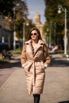 beautiful caucasian female advertising winter clothes, boots and sunglasses in the park