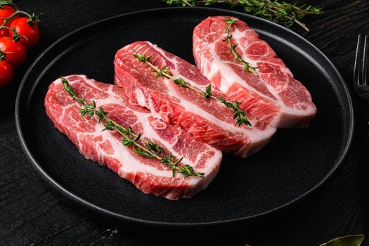Fresh pork neck meat steaks set, on black wooden table background