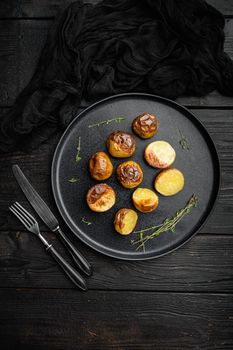 Baked potatoes set, on plate, on black wooden table background, top view flat lay