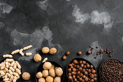 A variety of nuts, peanut, walnut, pine nuts and hazelnut set, on black dark stone table background, top view flat lay, with copy space for text