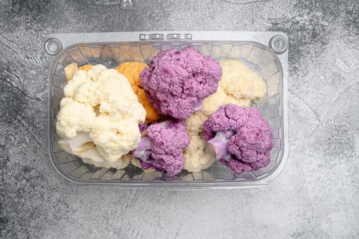 Fresh organic cauliflower cut into small pieces set, in container, on gray stone table background, top view flat lay