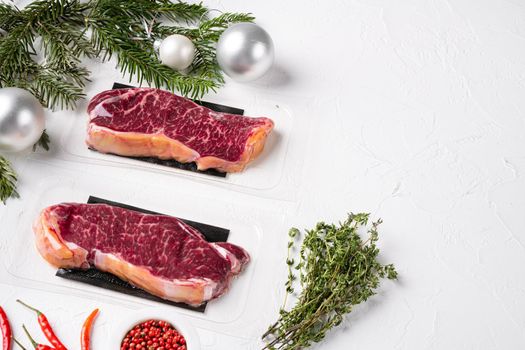 Raw steak with Christmas tree decorations set, on white stone table background, with copy space for text
