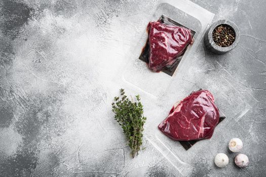 Beef steak vacuum sealed set, on gray stone table background, top view flat lay, with copy space for text